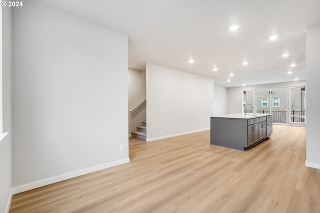 kitchen featuring light countertops, light wood-style flooring, a kitchen island with sink, and baseboards