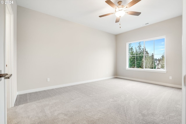 spare room featuring baseboards, visible vents, a ceiling fan, and light colored carpet