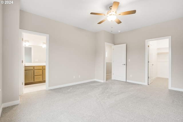 unfurnished bedroom featuring connected bathroom, a ceiling fan, baseboards, a spacious closet, and a closet