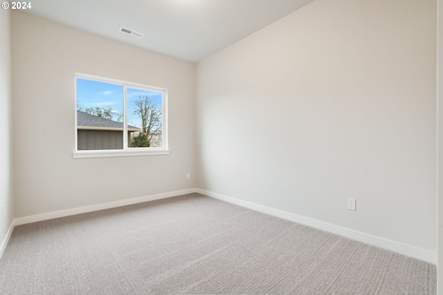 spare room featuring carpet floors, visible vents, and baseboards