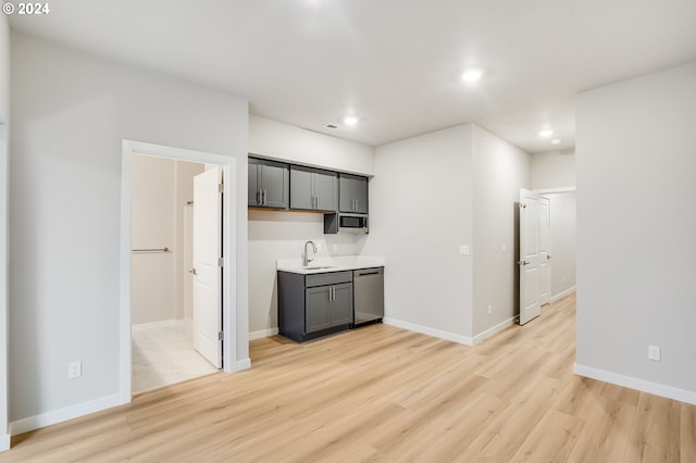 kitchen with light wood finished floors, light countertops, gray cabinetry, appliances with stainless steel finishes, and a sink