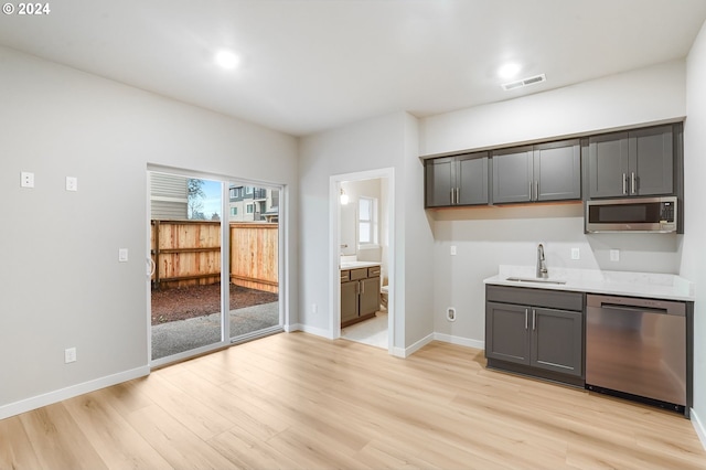 kitchen featuring stainless steel appliances, light countertops, visible vents, light wood-style floors, and a sink