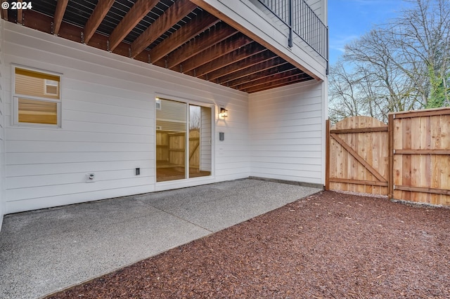 doorway to property with a patio area, fence, and a gate