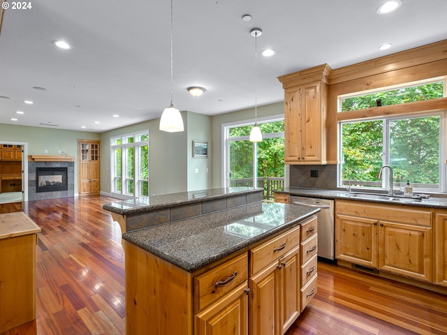 kitchen with stainless steel dishwasher, hardwood / wood-style floors, sink, and a kitchen island