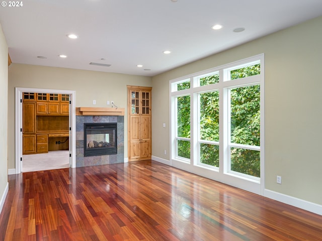 unfurnished living room featuring a tiled fireplace, hardwood / wood-style floors, and plenty of natural light