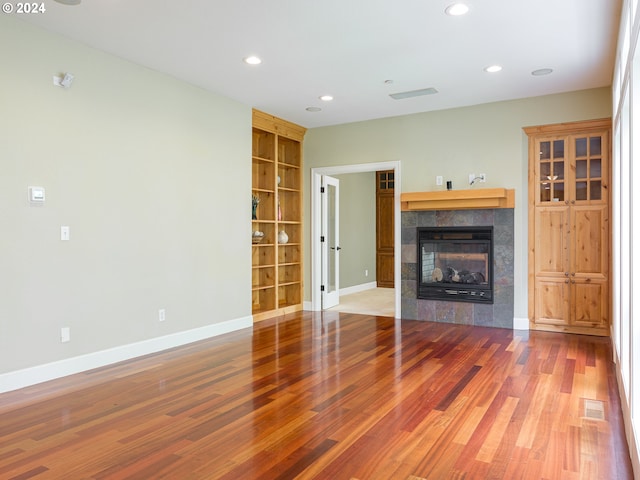 unfurnished living room featuring hardwood / wood-style floors, a fireplace, and built in features