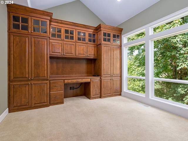 unfurnished office featuring built in desk, light colored carpet, and lofted ceiling