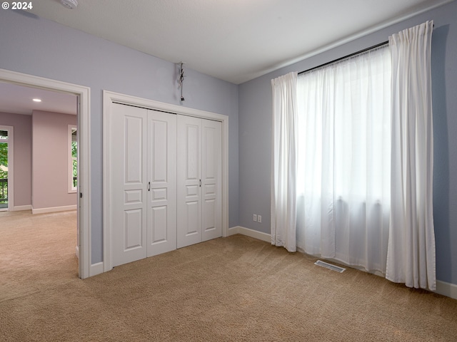 unfurnished bedroom with a closet and light colored carpet