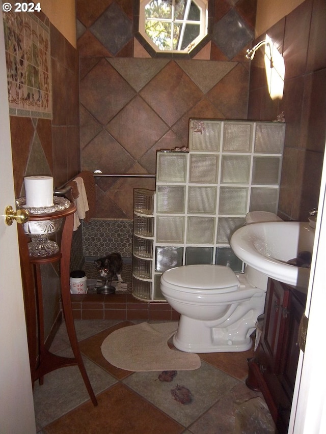 bathroom with tile patterned flooring, toilet, walk in shower, vanity, and tile walls