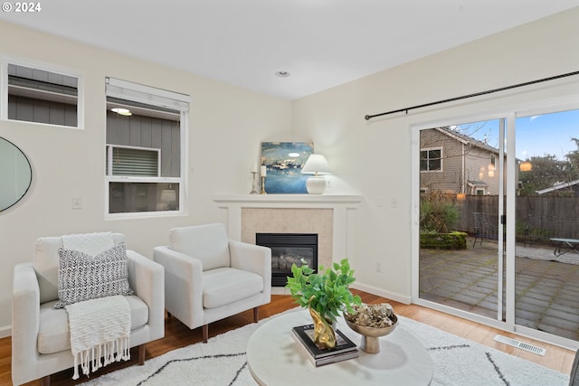 living room with a tile fireplace and wood-type flooring