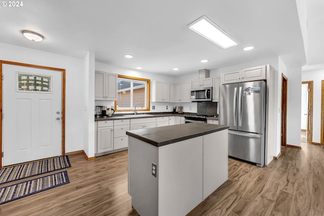 kitchen with light hardwood / wood-style floors, sink, white cabinets, and stainless steel appliances