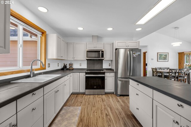 kitchen featuring decorative light fixtures, sink, white cabinets, and stainless steel appliances