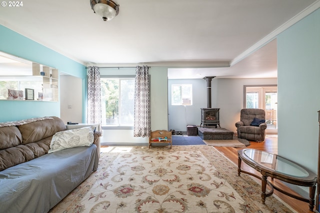 living room with ornamental molding, hardwood / wood-style floors, and a wood stove