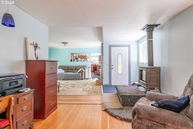 bedroom with light wood-type flooring, a wood stove, and multiple windows