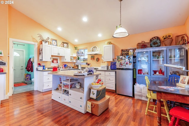 kitchen with decorative light fixtures, white cabinets, stainless steel fridge, and lofted ceiling