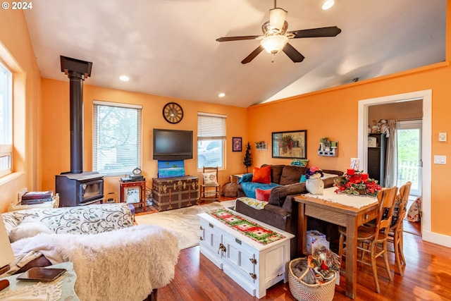 living room with ceiling fan, dark hardwood / wood-style flooring, vaulted ceiling, and a wood stove