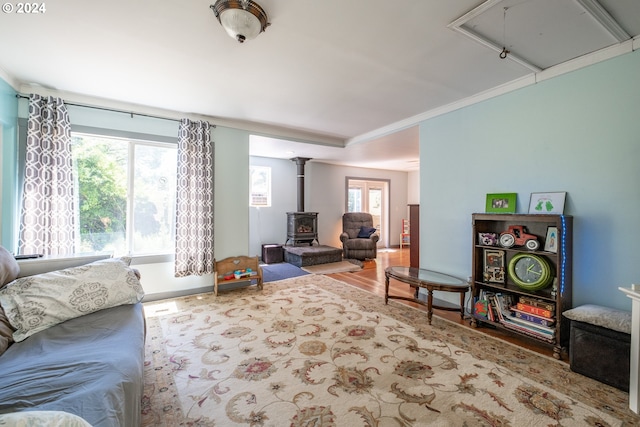 living room featuring hardwood / wood-style floors, crown molding, and a wood stove