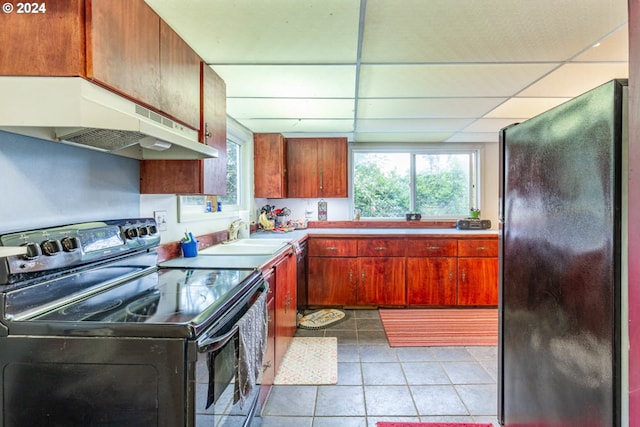 kitchen featuring black appliances, light tile patterned floors, sink, and a drop ceiling