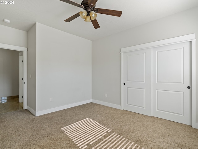 unfurnished bedroom featuring light colored carpet, ceiling fan, and a closet