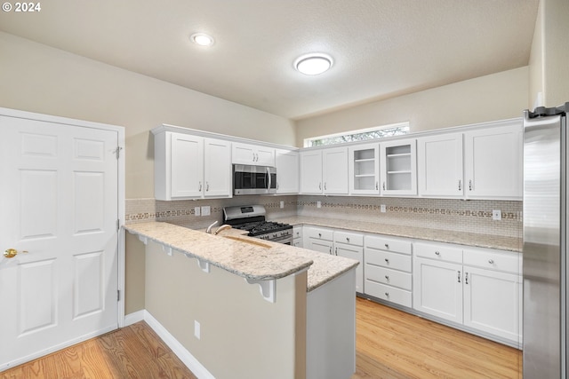 kitchen featuring a breakfast bar area, kitchen peninsula, white cabinets, and stainless steel appliances