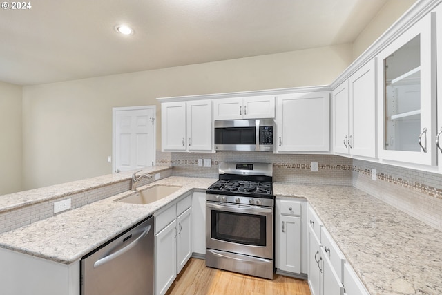 kitchen featuring backsplash, sink, light hardwood / wood-style floors, white cabinetry, and stainless steel appliances