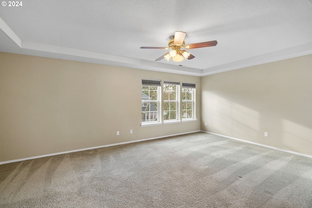 spare room with a raised ceiling, ceiling fan, carpet floors, and a textured ceiling