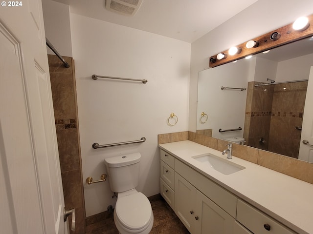 bathroom featuring vanity, toilet, and a tile shower