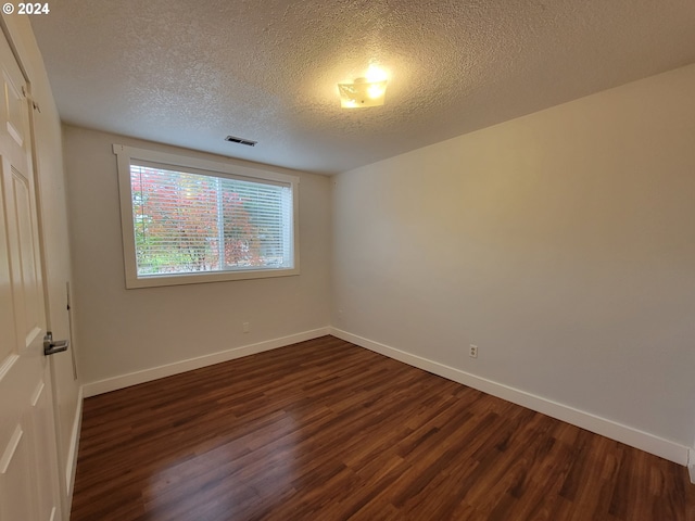 spare room with dark wood-type flooring and a textured ceiling