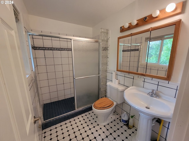 bathroom featuring backsplash, a shower with door, tile walls, toilet, and tile patterned flooring