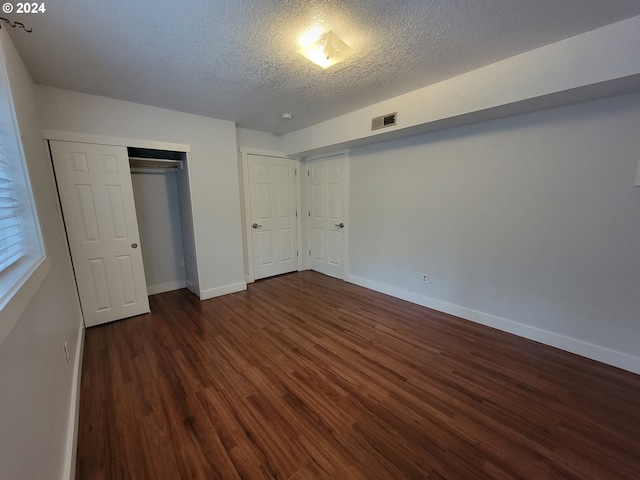 unfurnished bedroom with a closet, dark hardwood / wood-style floors, and a textured ceiling