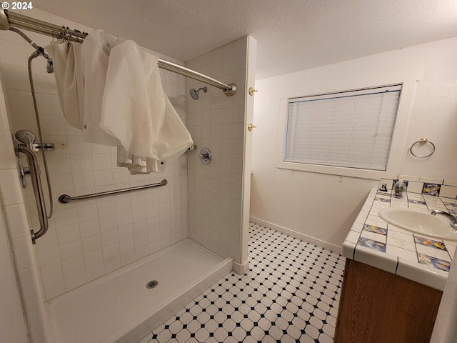 bathroom featuring vanity, a tile shower, and tile patterned floors