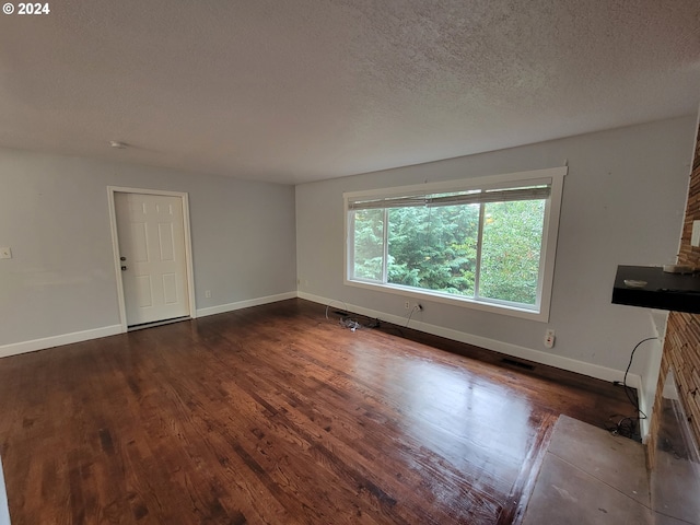 unfurnished living room featuring a textured ceiling and dark hardwood / wood-style flooring