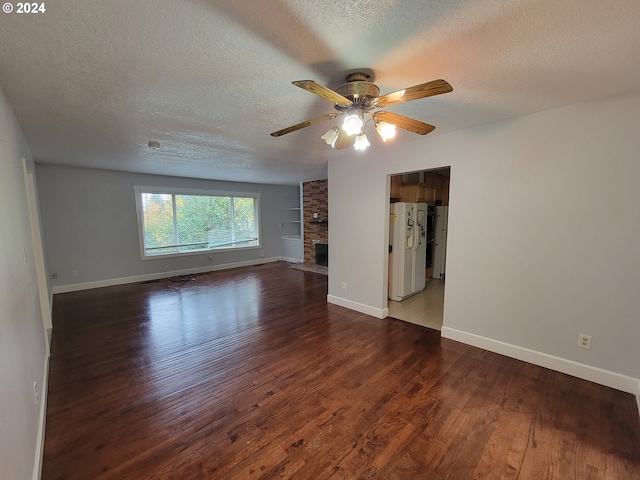 spare room with dark wood-type flooring, ceiling fan, a textured ceiling, and a fireplace