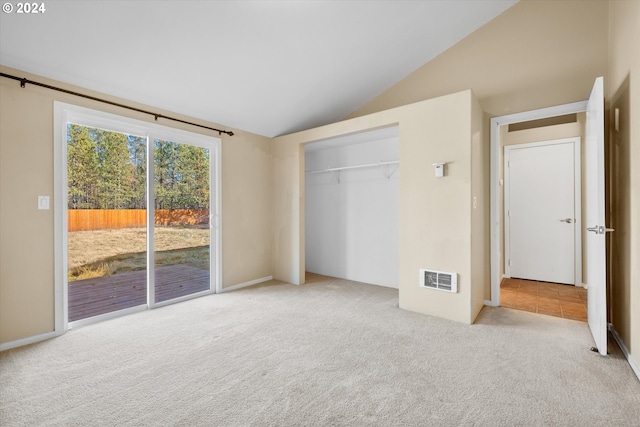 unfurnished bedroom featuring vaulted ceiling, light carpet, access to exterior, and a closet