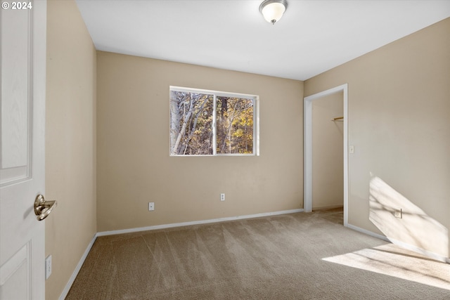 unfurnished bedroom with a closet, light carpet, and a spacious closet