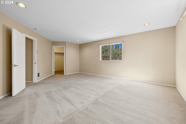 unfurnished bedroom with a walk in closet, a closet, and light colored carpet