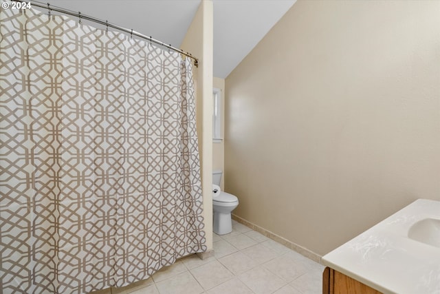 bathroom with toilet, vanity, tile patterned floors, and vaulted ceiling