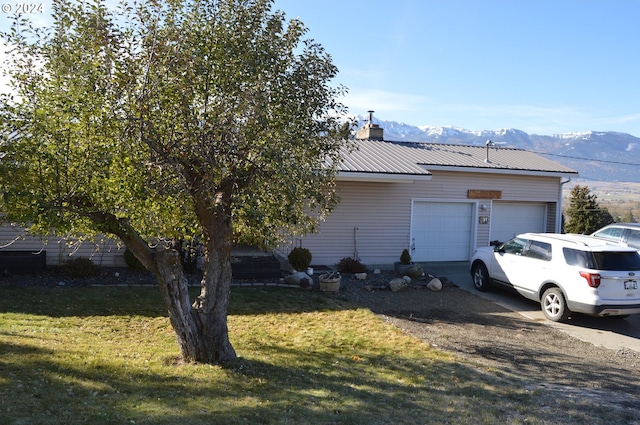 exterior space with a garage, a mountain view, and a front lawn