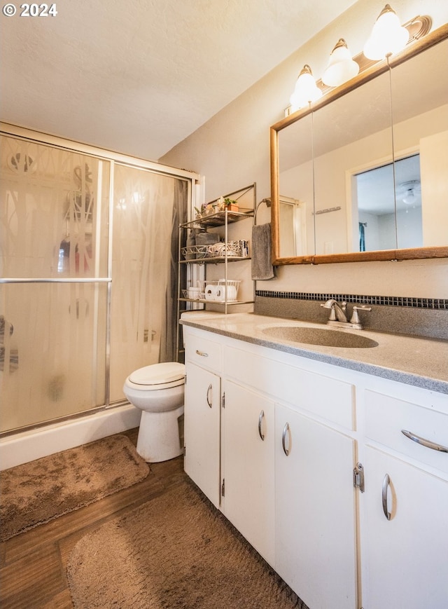 bathroom featuring hardwood / wood-style floors, vanity, an enclosed shower, and toilet