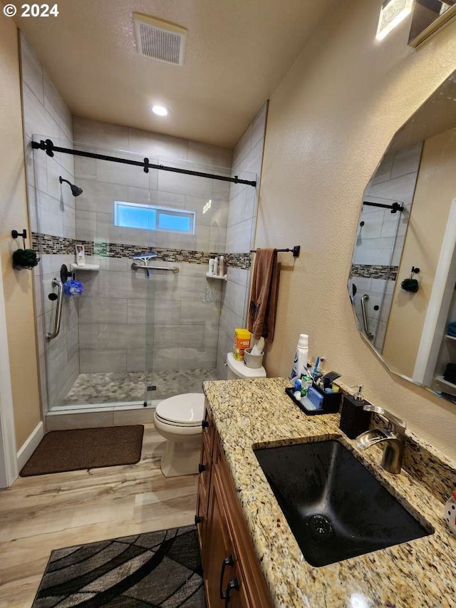 bathroom with vanity, hardwood / wood-style flooring, toilet, and a shower with shower door