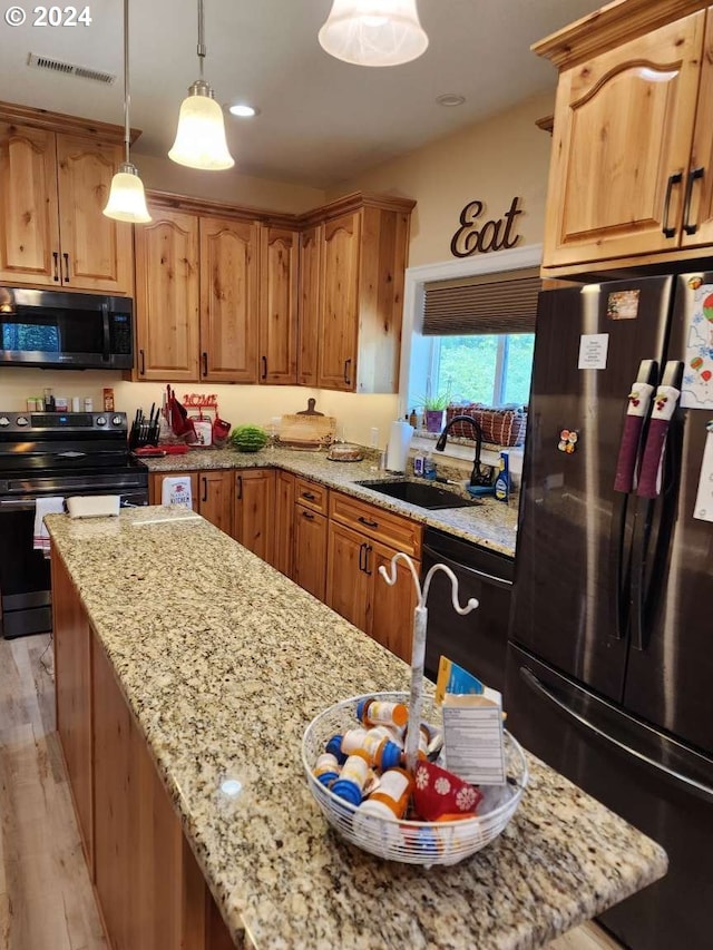 kitchen with light stone countertops, sink, black appliances, light hardwood / wood-style floors, and hanging light fixtures