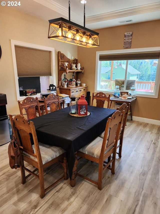 dining area featuring light hardwood / wood-style floors, ornamental molding, and a chandelier