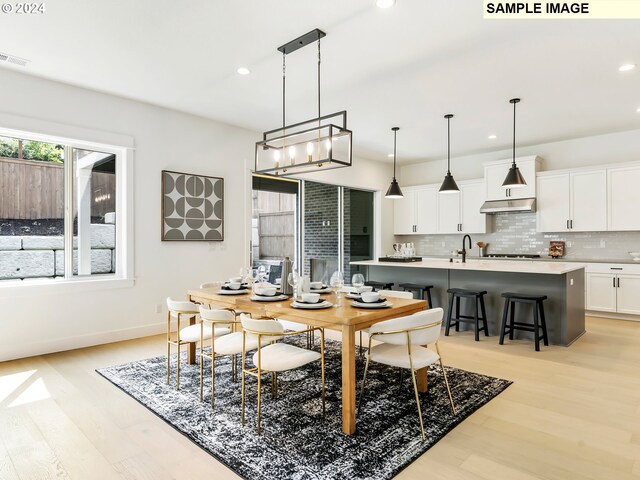 dining space featuring sink, light hardwood / wood-style flooring, and a notable chandelier