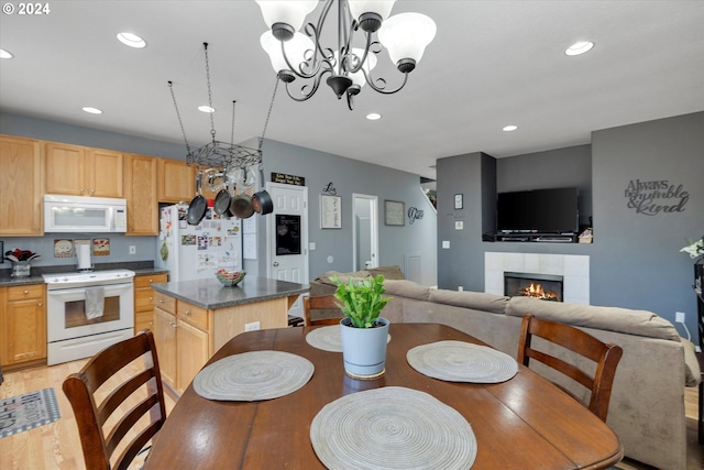 dining space featuring light hardwood / wood-style flooring, an inviting chandelier, and a tiled fireplace