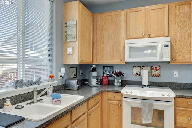 kitchen with light brown cabinets, white appliances, and sink