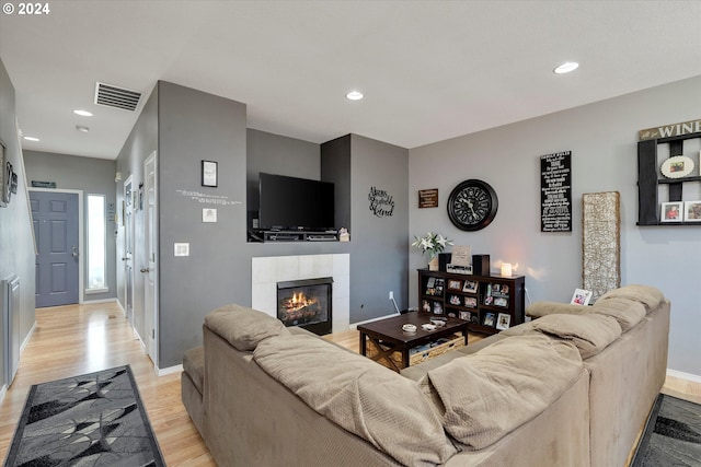 living room with a tile fireplace and light wood-type flooring