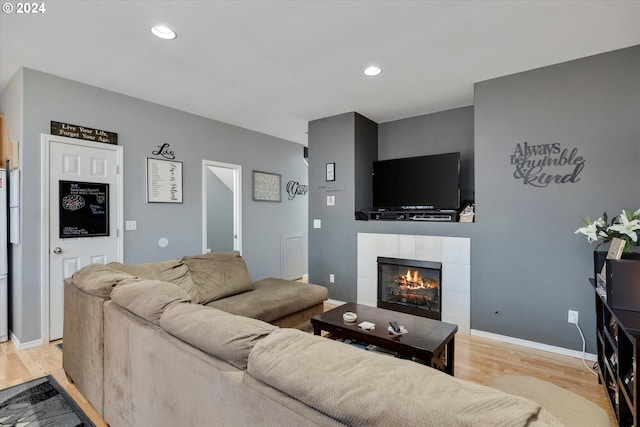 living room with light hardwood / wood-style floors and a tiled fireplace