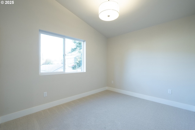 carpeted empty room featuring vaulted ceiling