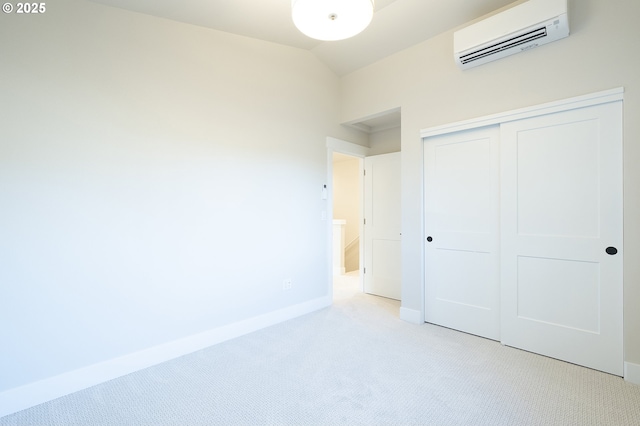 unfurnished bedroom with lofted ceiling, a wall mounted air conditioner, a closet, and light carpet