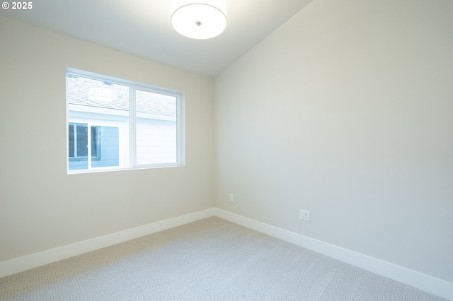 carpeted spare room with vaulted ceiling